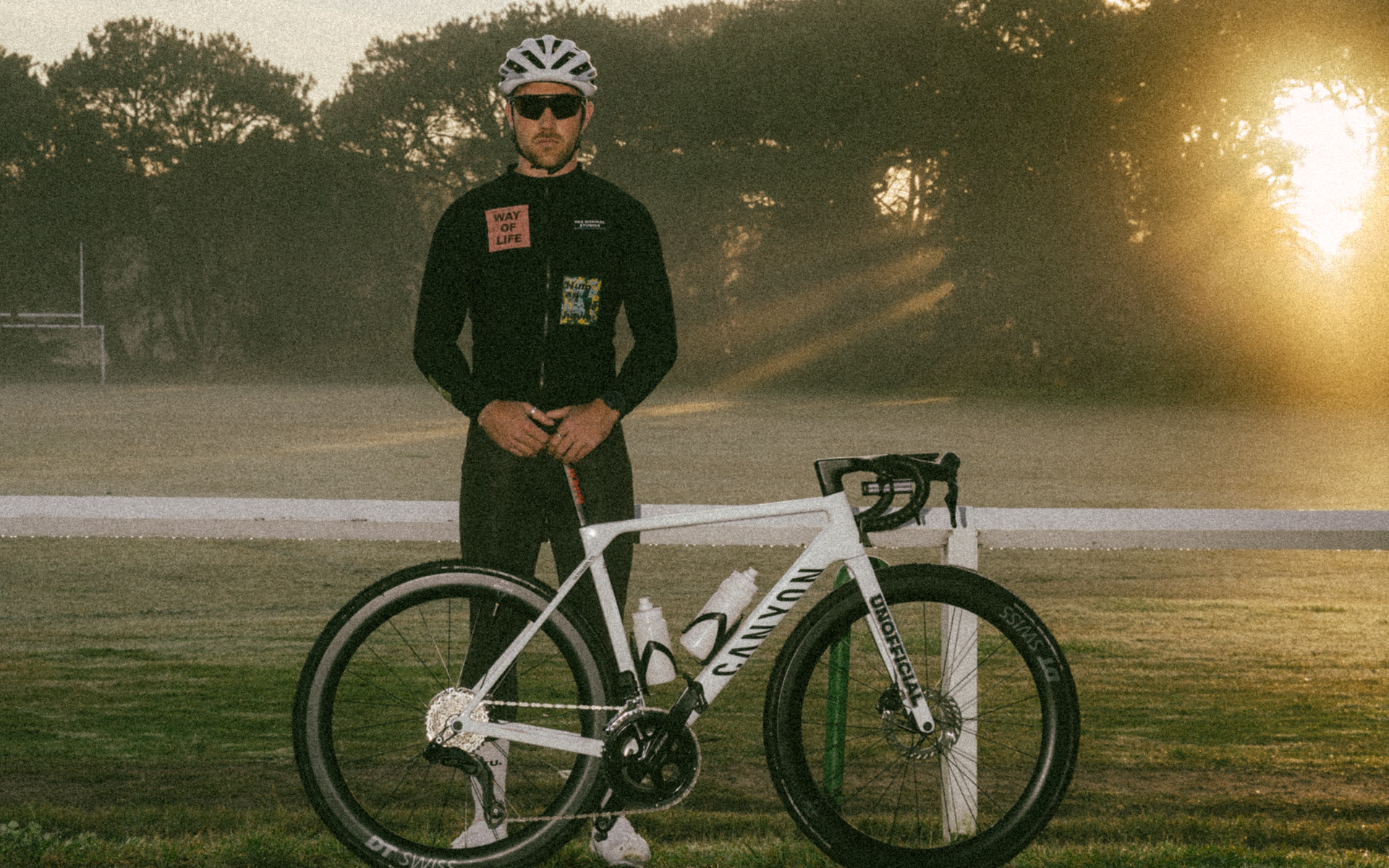 Cyclist standing with a road bike in warm evening light