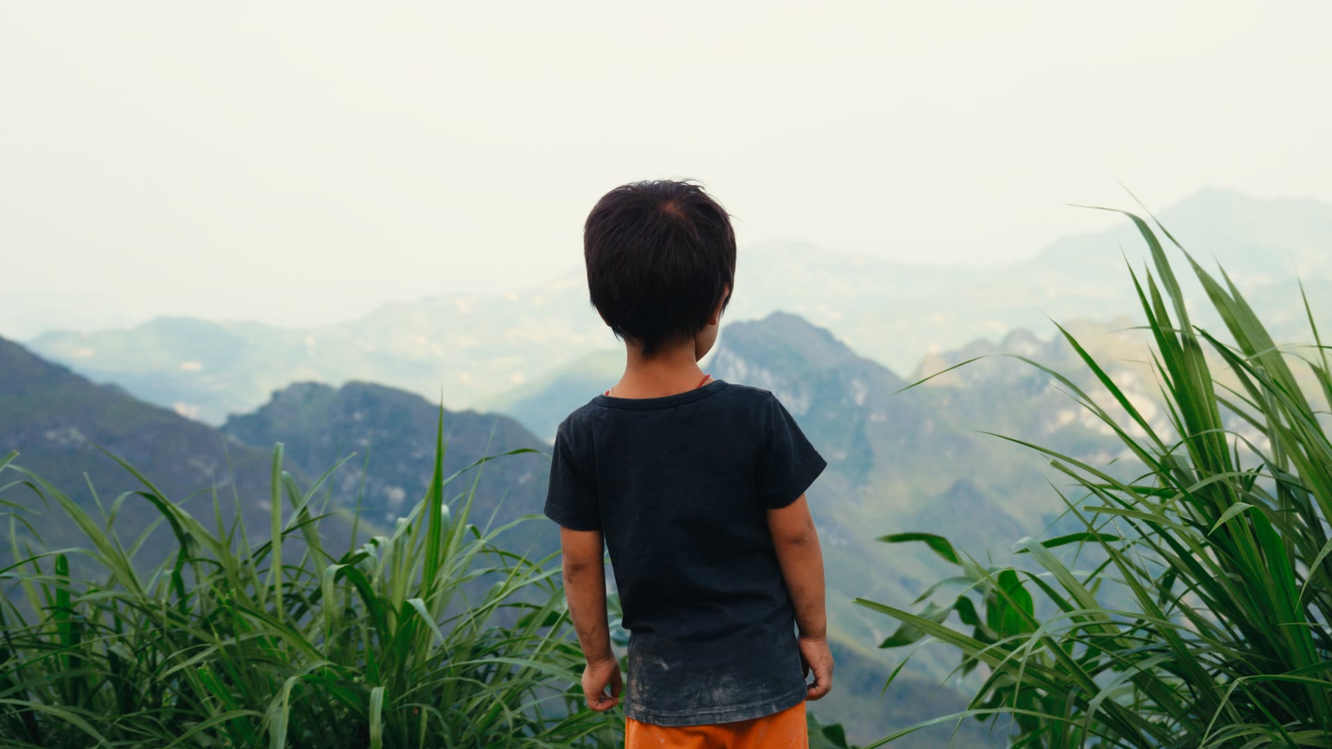 A child looking across a green mountain landscape