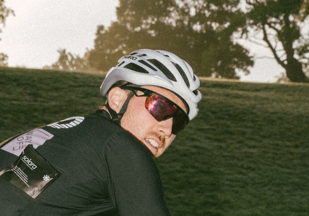 Cyclist in a white helmet grinning at the camera
